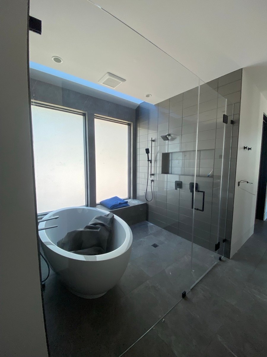 Full shower tile installation with a frameless glass enclosure and freestanding tub