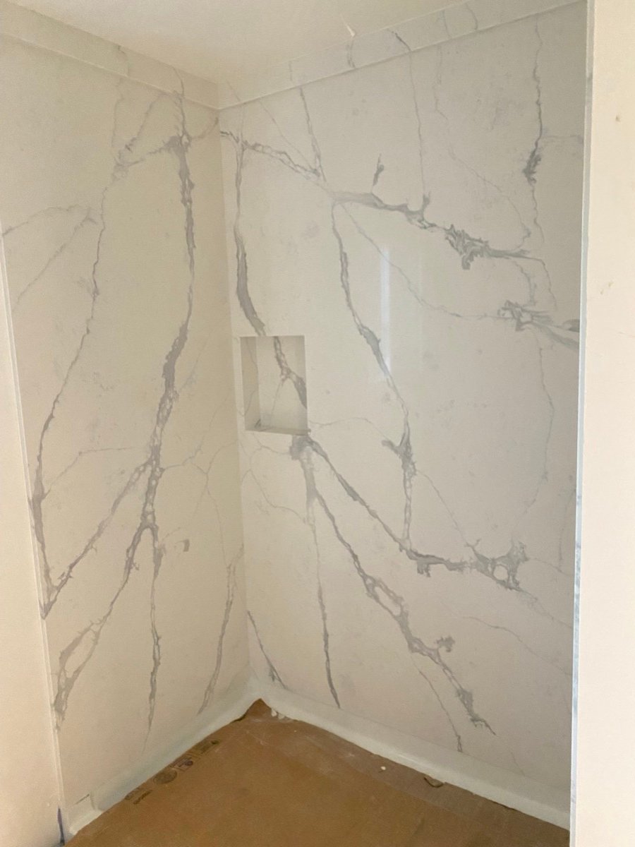 Shower with marble-look slab walls and a built-in niche