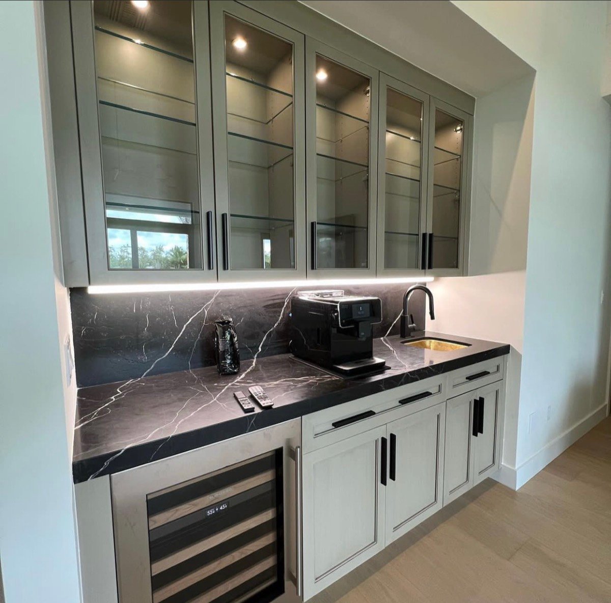 Wet bar with a black marble countertop and backsplash