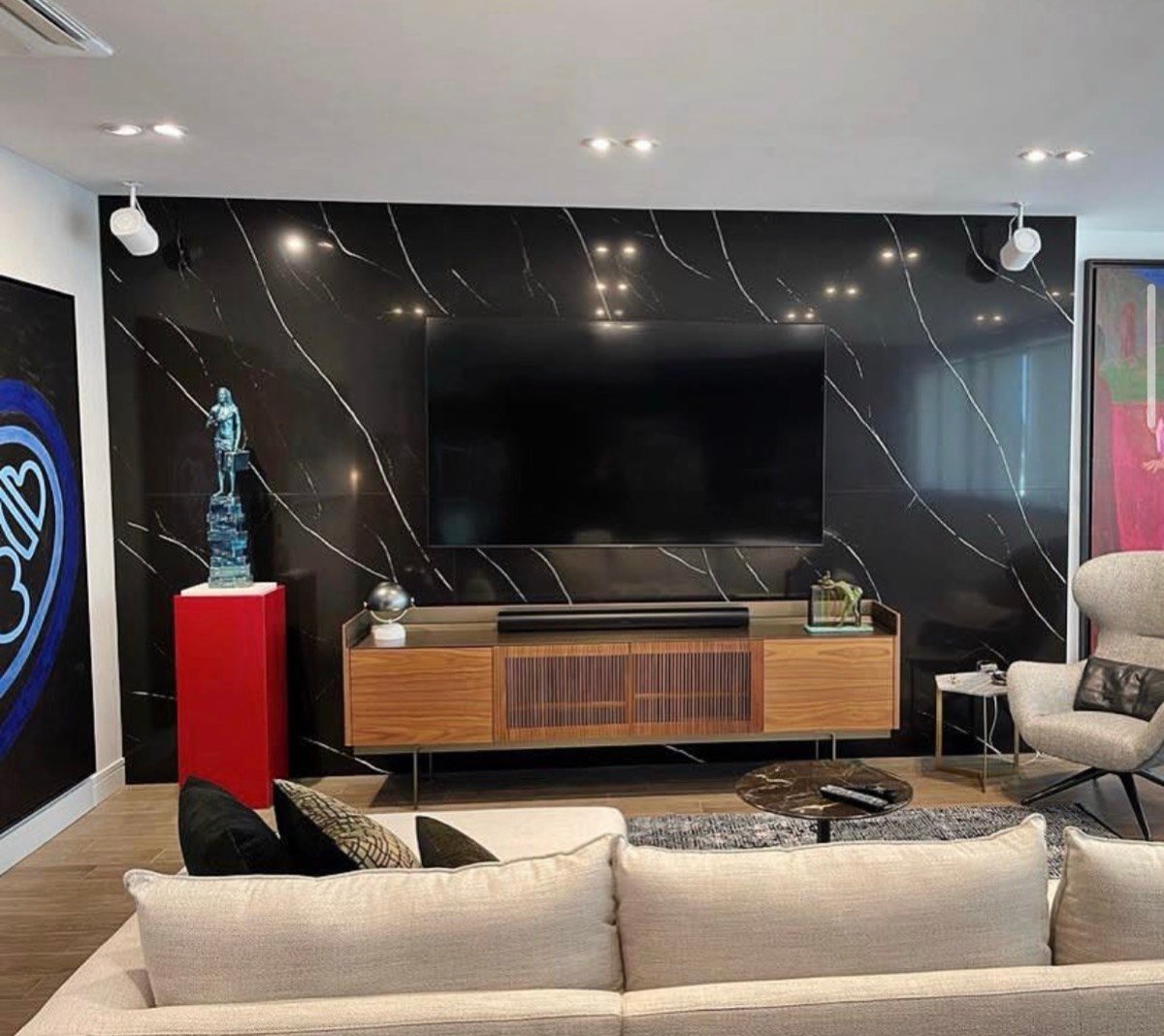 Custom black and white marble media wall styled with a sculpture, artwork, and built-in cable management
