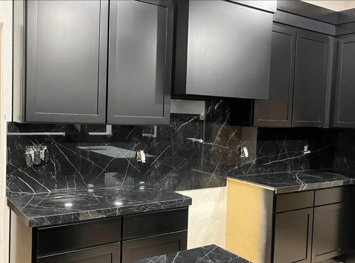 Black marble-look kitchen backsplash partway through installation
