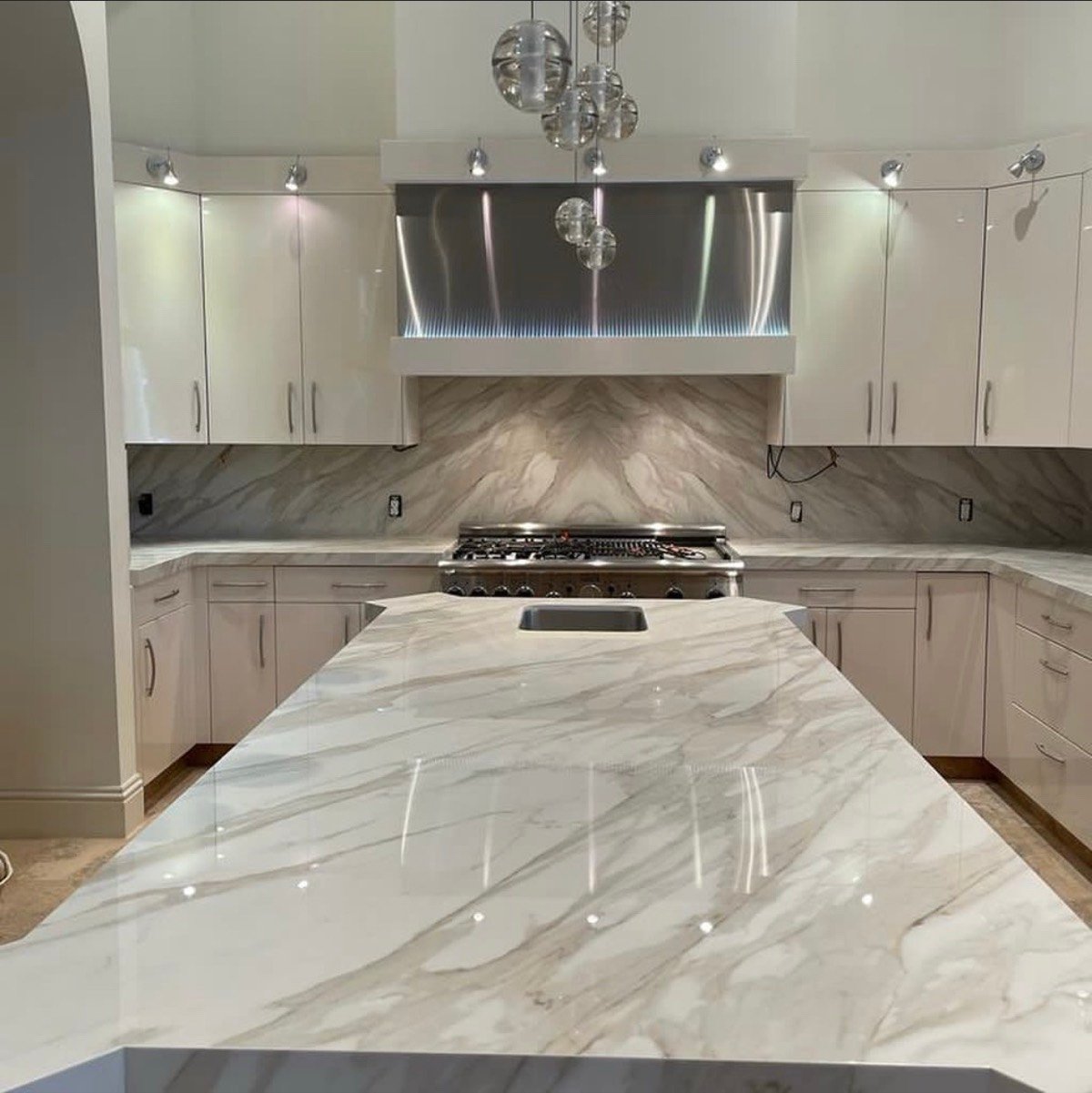 Kitchen with a bookmatched marble backsplash and waterfall island