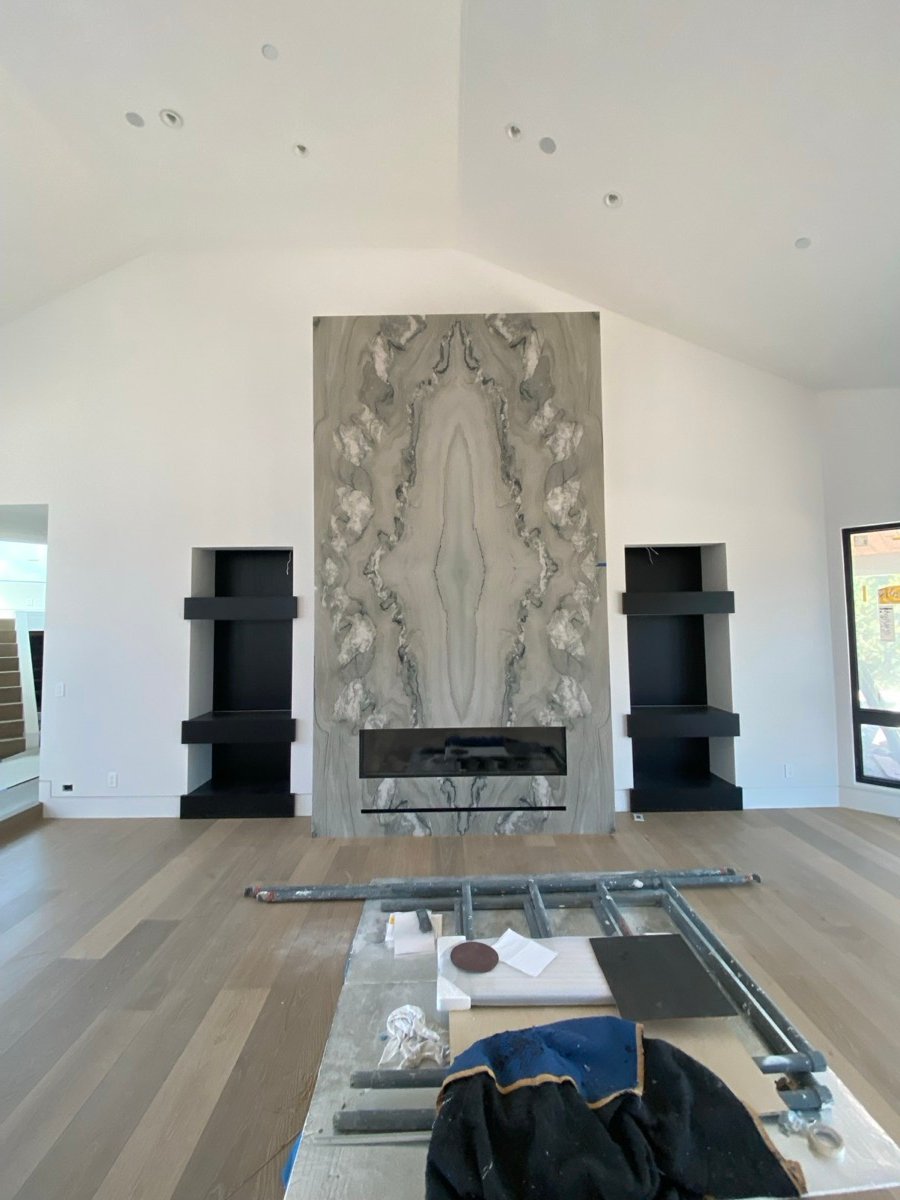 Black porcelain slab fireplace surround with a linear insert and herringbone wood flooring