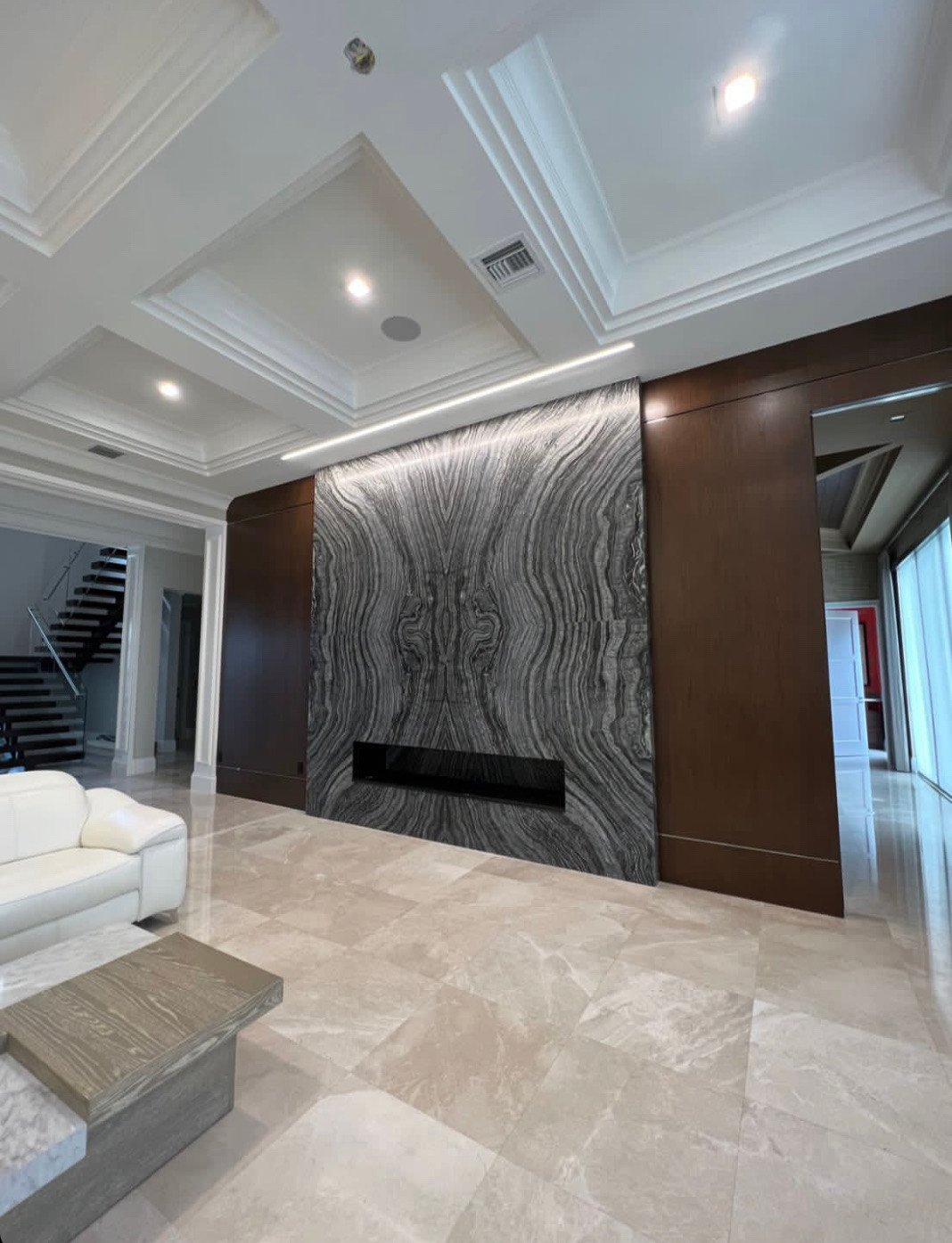 Living room with a floor-to-ceiling bookmatched stone fireplace wall