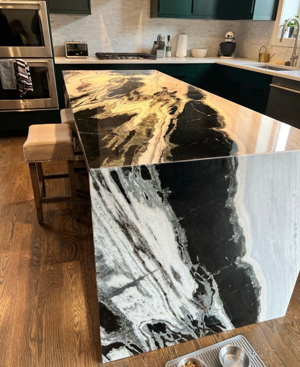 Kitchen island with a dramatic gold, black, and white exotic granite waterfall countertop